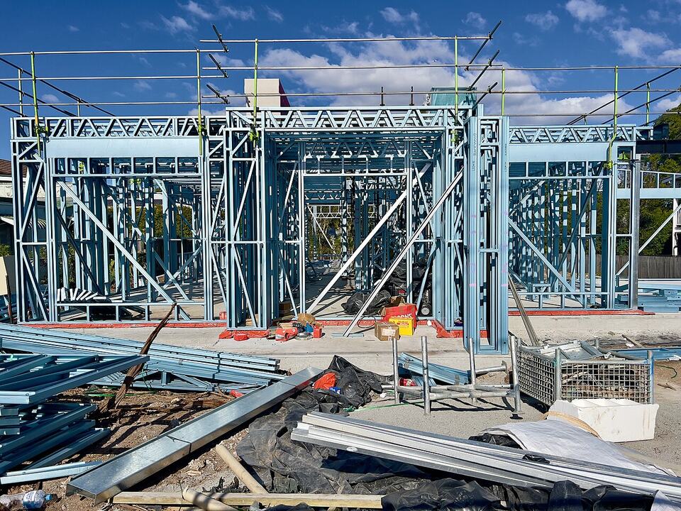 Steel house frame going up against a blue sky in Sherwood, Brisbane. New builds are the one category that keeps full negative gearing and the CGT discount under the 2027 rules.